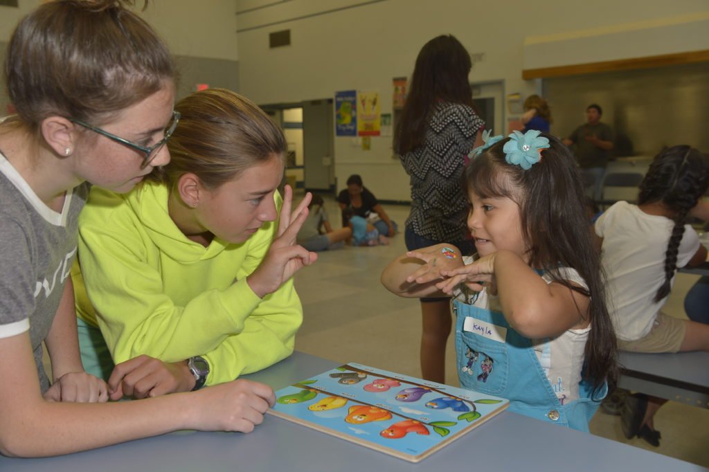 W.E. Care students Kayla and Piper playing a game with Lake Los Angeles resident Kayla